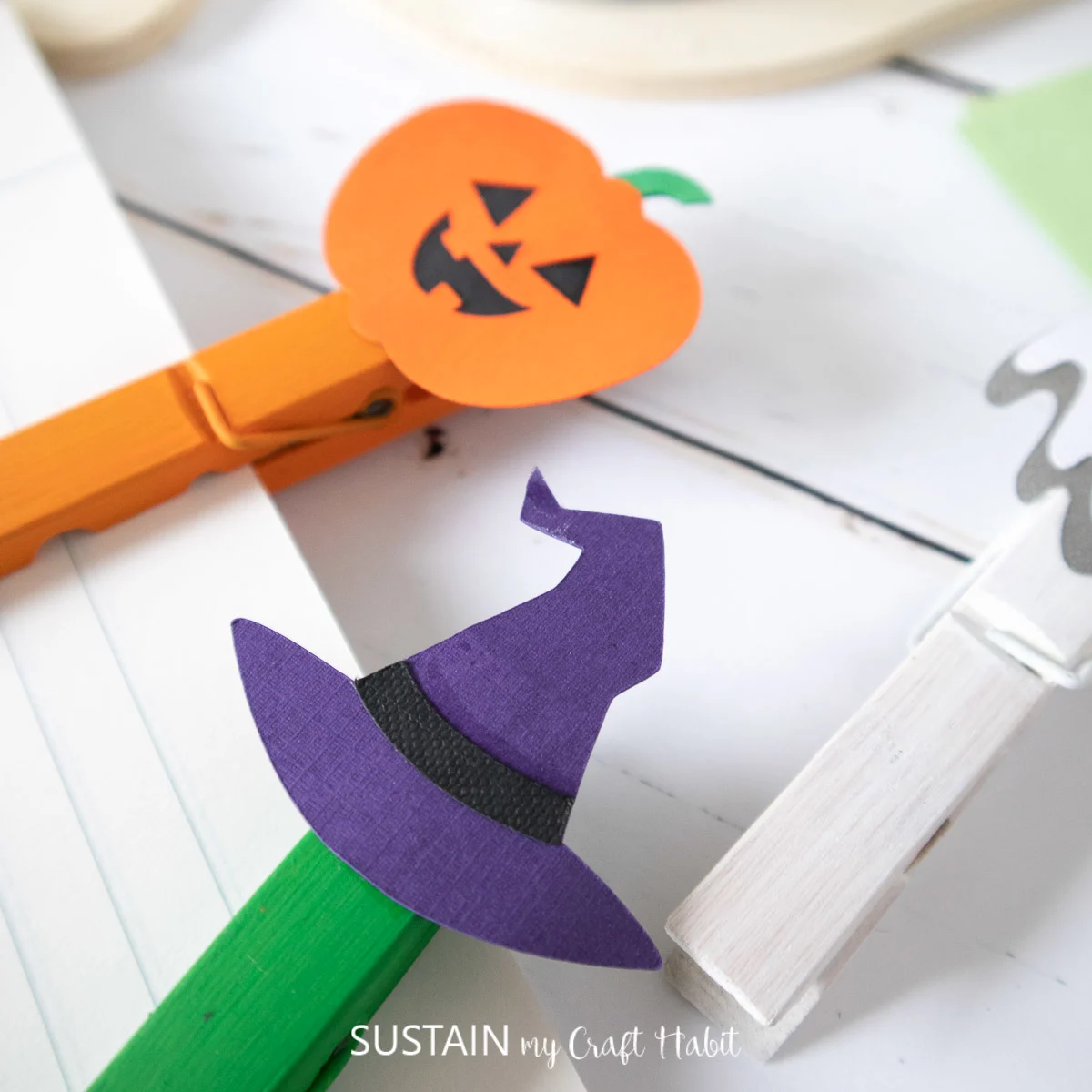 Completed pumpkin and witch's hat clothespin crafts being used to hold papers together.