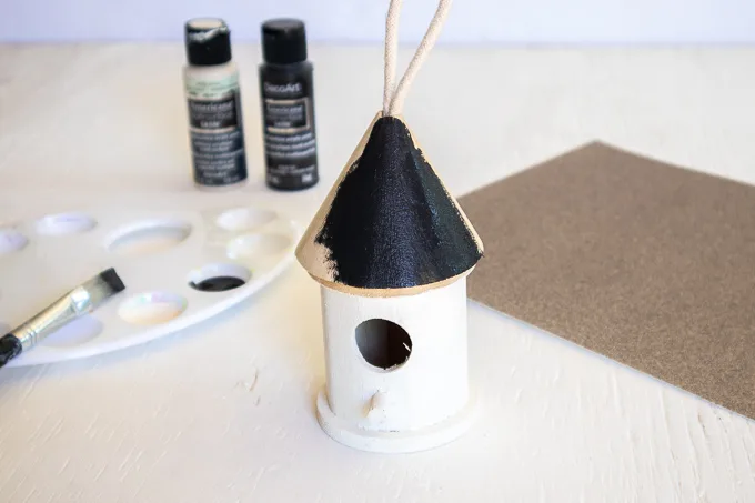 Painting the wooden birdhouse roof black.