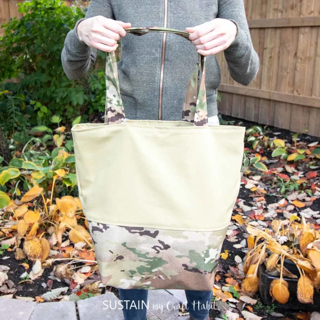 showing off a large two-fabric camo tote bag with a reinforced base with coated camouflage material and the upper panel in cotton canvas