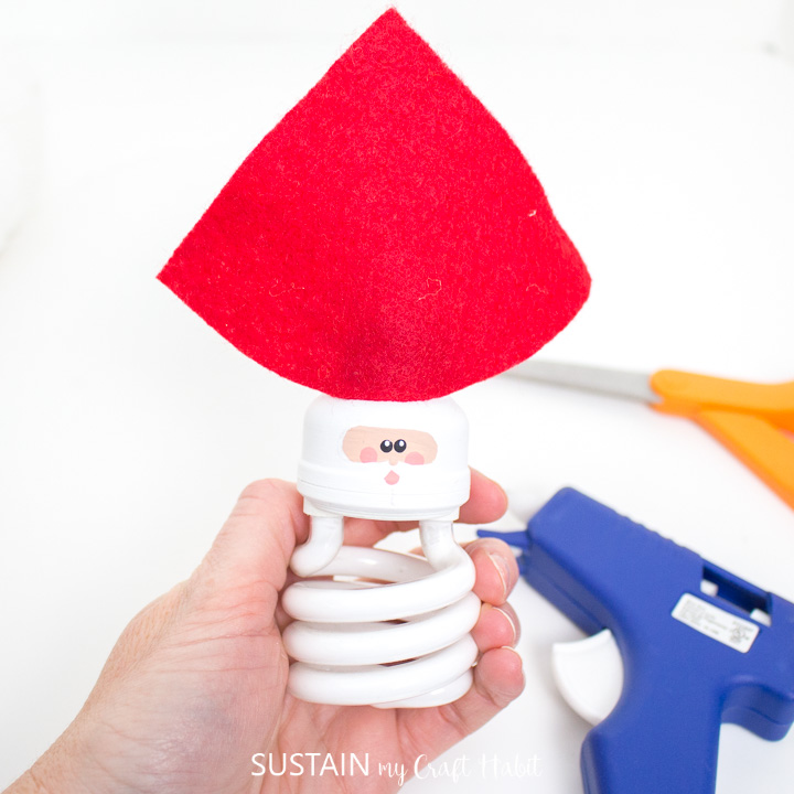 Gluing red felt fabric to the hot glue on the light bulb.