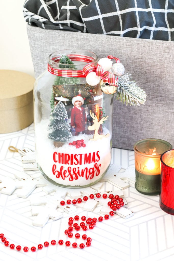 Pickle jar Christmas terrarium with decorative ribbon, Christmas accessories, fake snow and a picture.