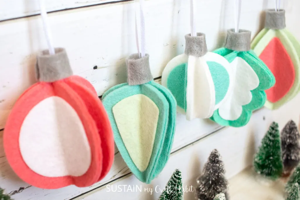 Retro inspired 3D felt Christmas ornaments hanging next to a wall.