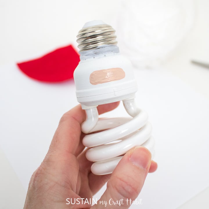 Painting a rounded rectangular shape on one side of the painted light bulb. 