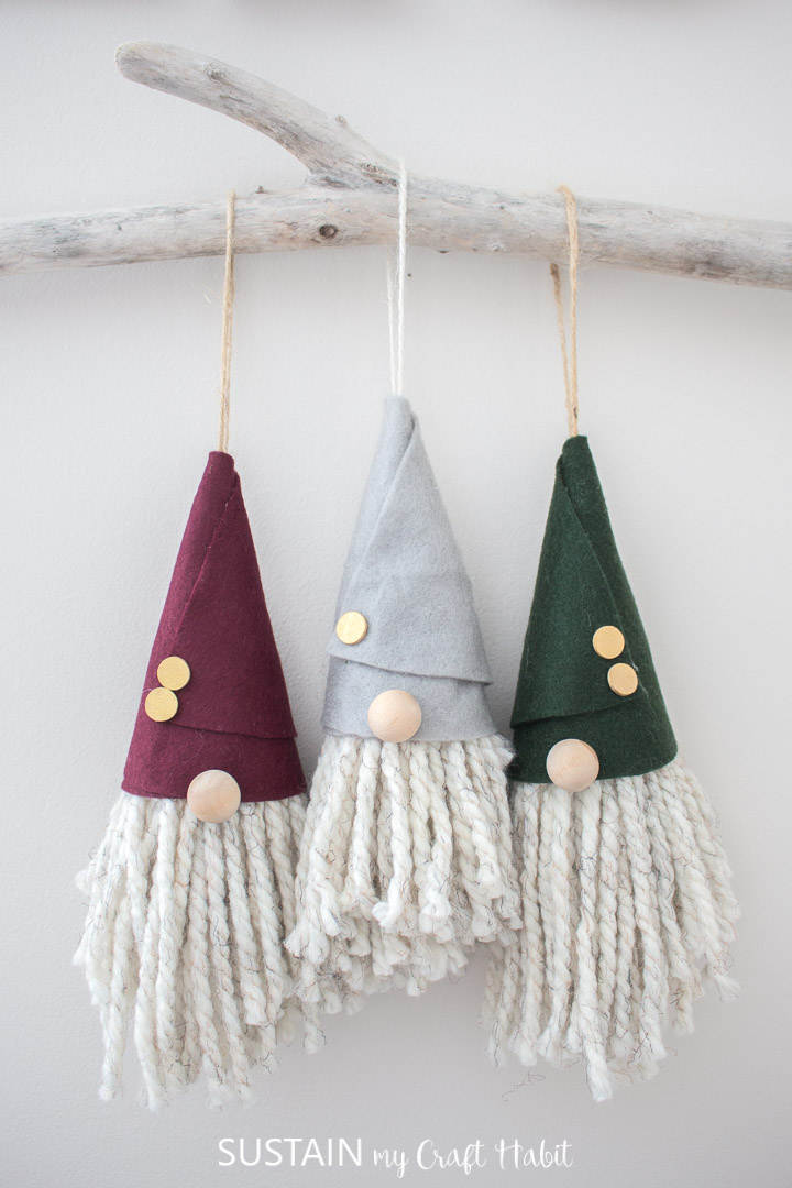 Gnome Christmas ornaments hanging on a tree branch.