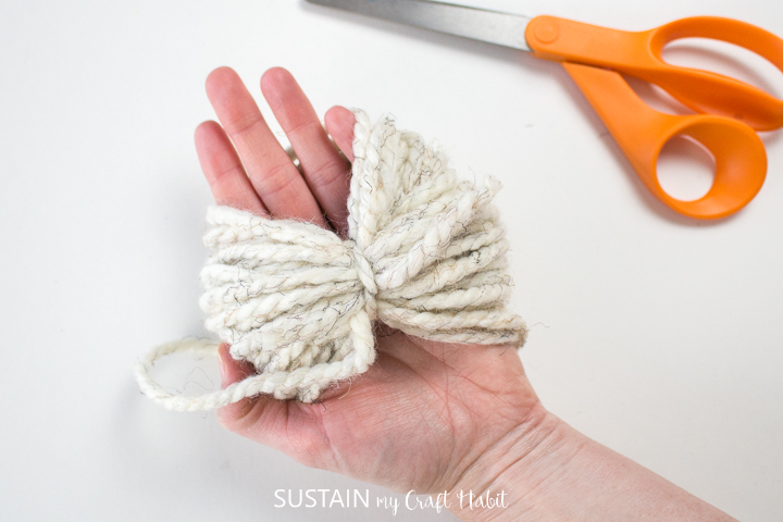 Tying a strand of yarn around the wrapped yarn.
