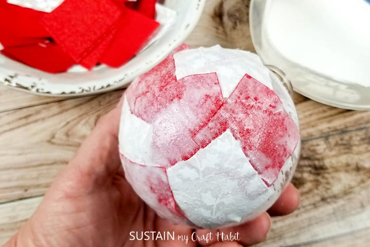 Gluing fabric squares onto a glass ornament.