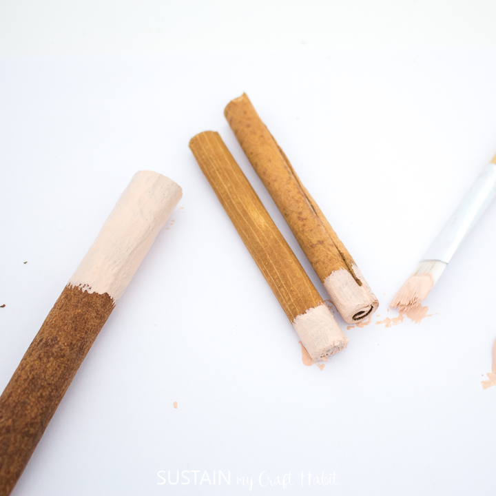Painting the bottoms of cinnamon sticks.