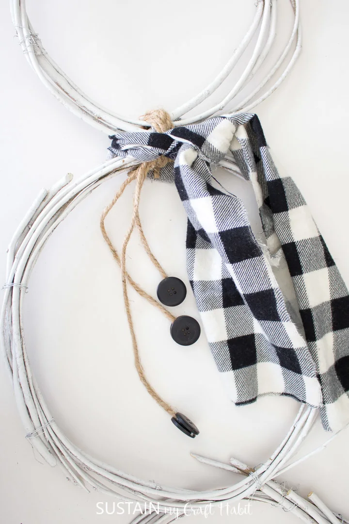 Tying the plaid fabric to the snowman wreath.