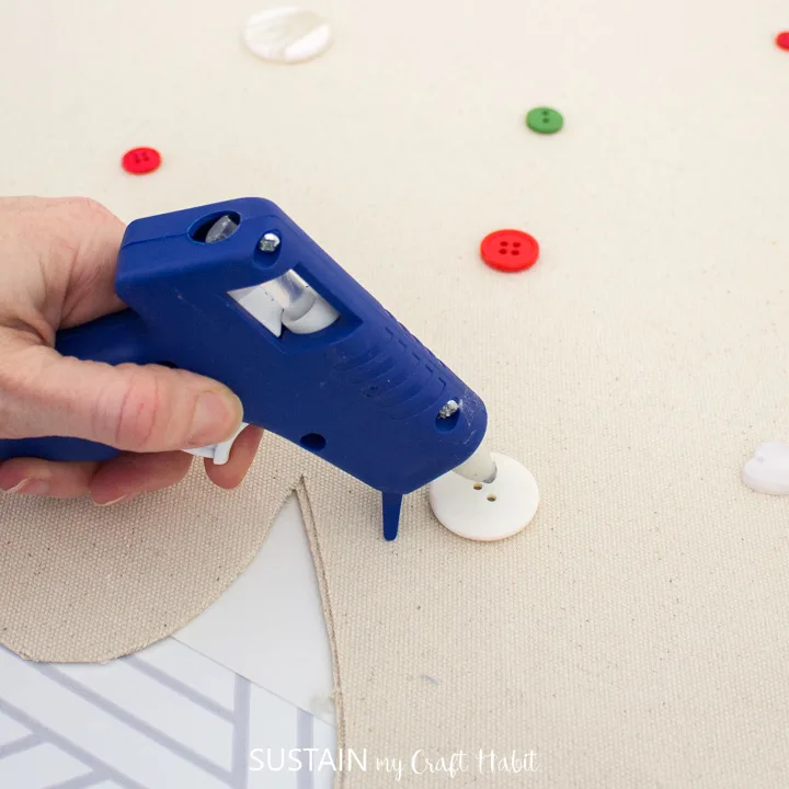 Hot gluing buttons onto the canvas Christmas tree.
