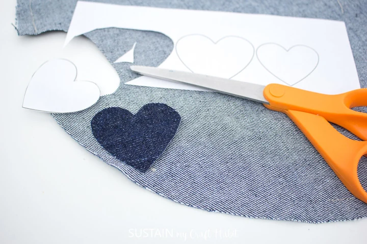 Cutting out denim hearts around the paper pattern.