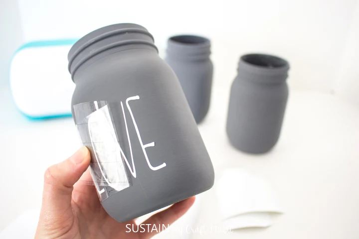 Peeling away the transfer tape from the chalky painted mason jar.