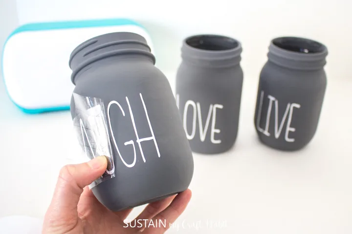 Peeling away the excess transfer tape from the remaining chalky painted mason jars.