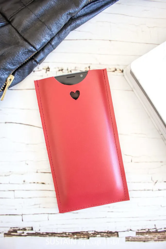 A cell phone inserted into a red leather phone sleeve.