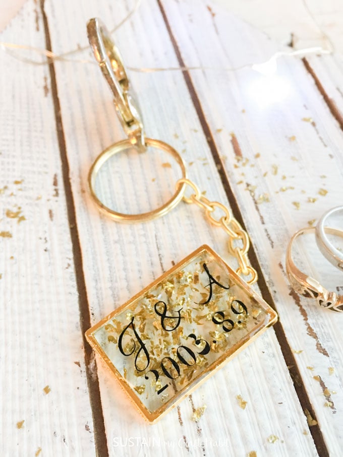 Resin keychain with gold flakes laid on a wood background. 