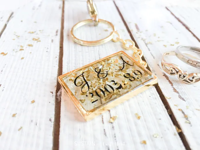 Resin keychain with gold flakes laid on a wood background. 
