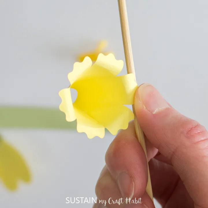 Using a wooden dowel to curl the edges of the paper flower.