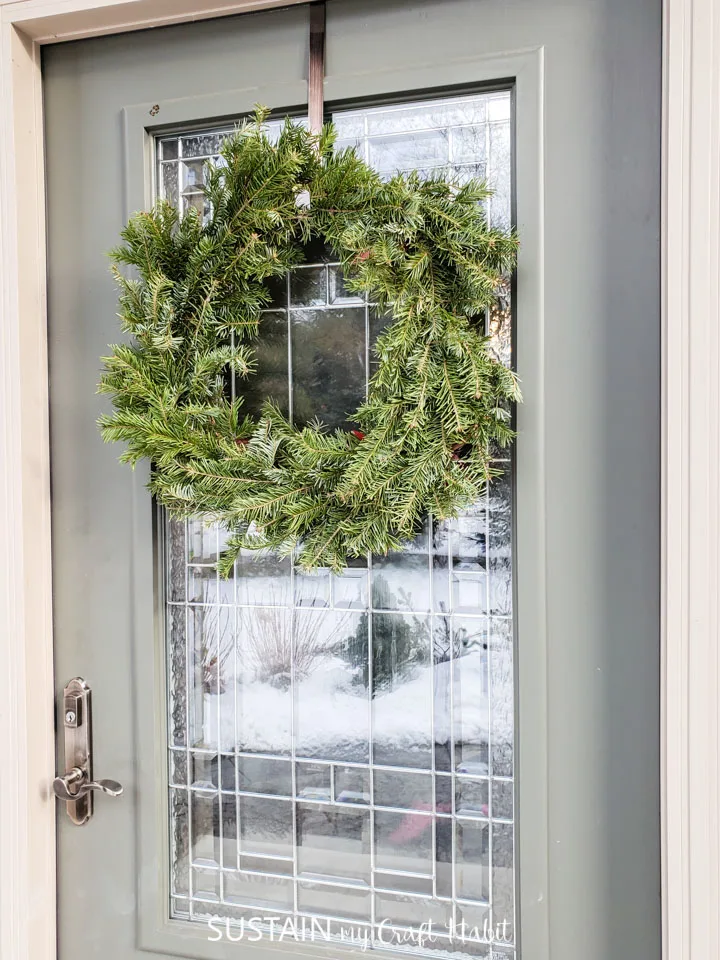An evergreen wreath hanging from a door.