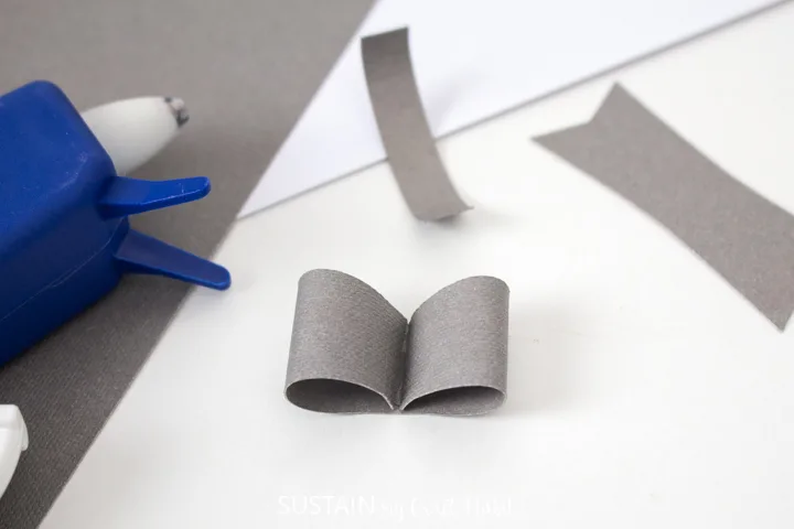 Folding the curled edges into the middle of the paper bow.