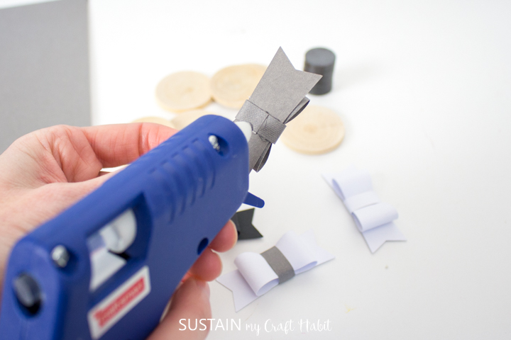 Adding hot glue to the back of a paper bow.