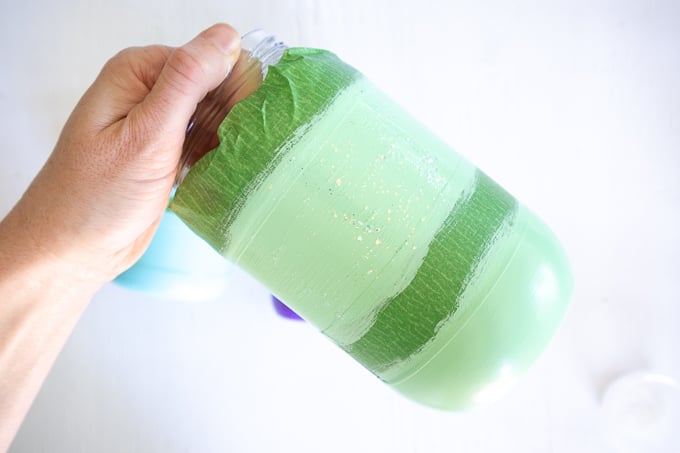 Adding glitter paint to the green painted mason jar.