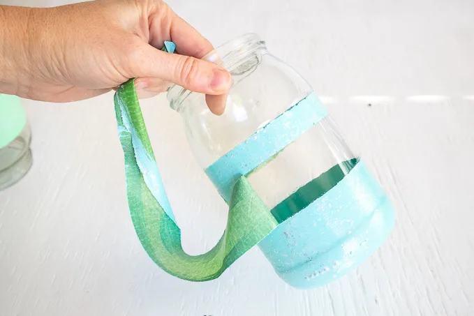 Removing the green painters tape from the mason jar.