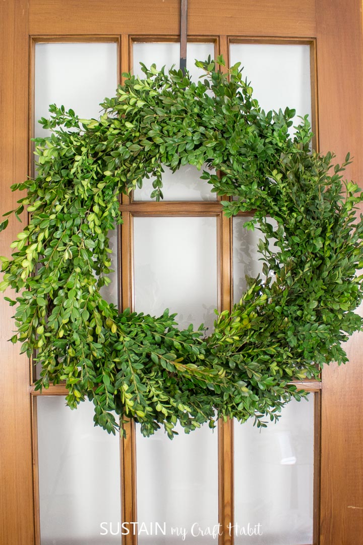 Boxwood wreath hanging on a wooden door.