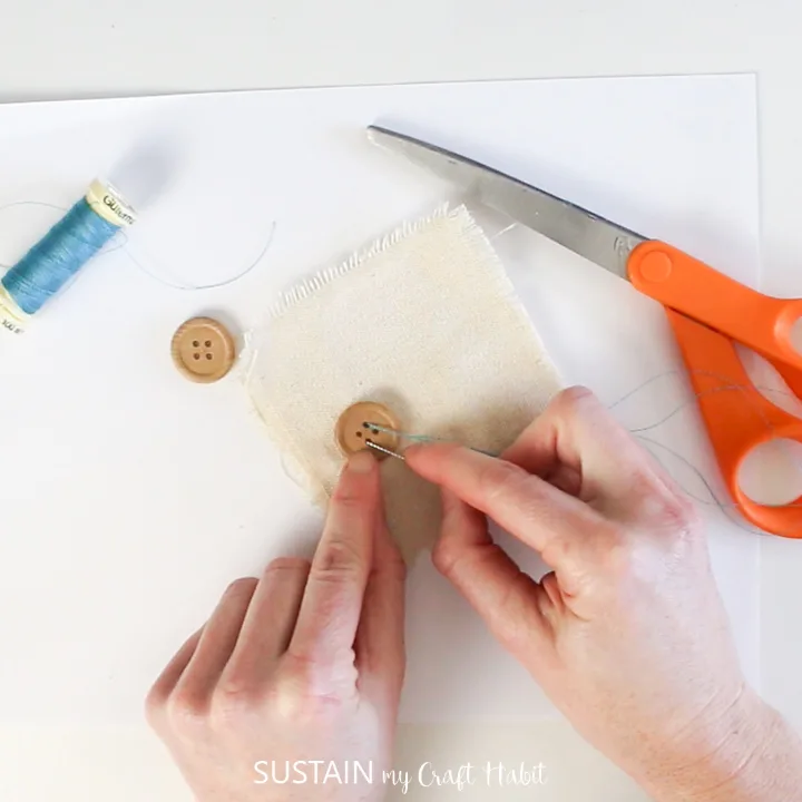 Sewing a button onto canvas fabric.