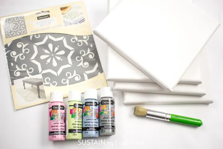 Materials needed to make Mediterranean tile stencil art including paint, paint brushes, canvas boards and a stencil.