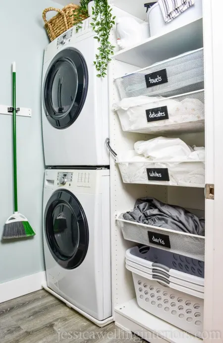 Stacked washer and dryer next to an organized wardrobe.