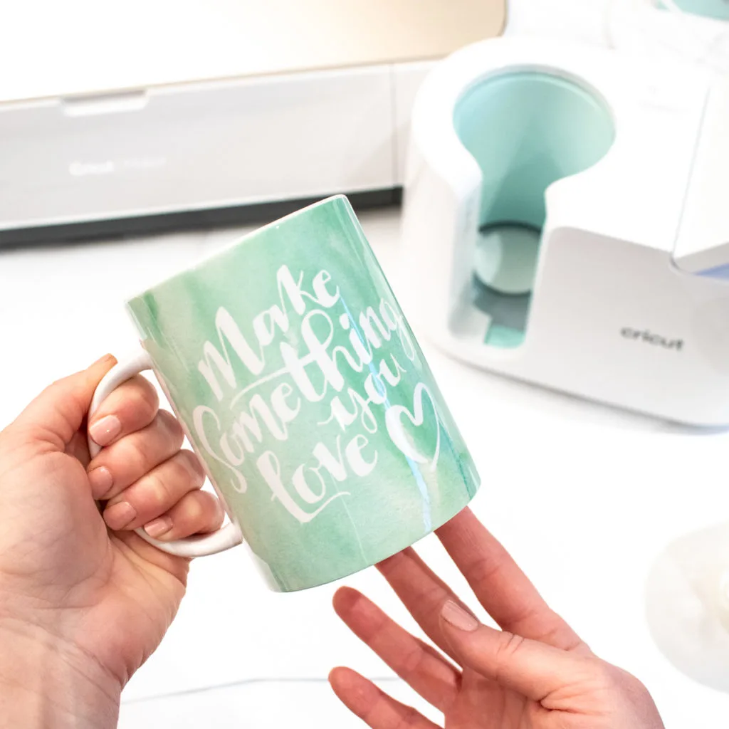 Close up image of a large mug with a green watercolor ink sublimation design and phrase reading Make Something you Love.