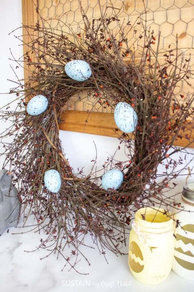 Rustic birds nest twig wreath with decorative Easter eggs.