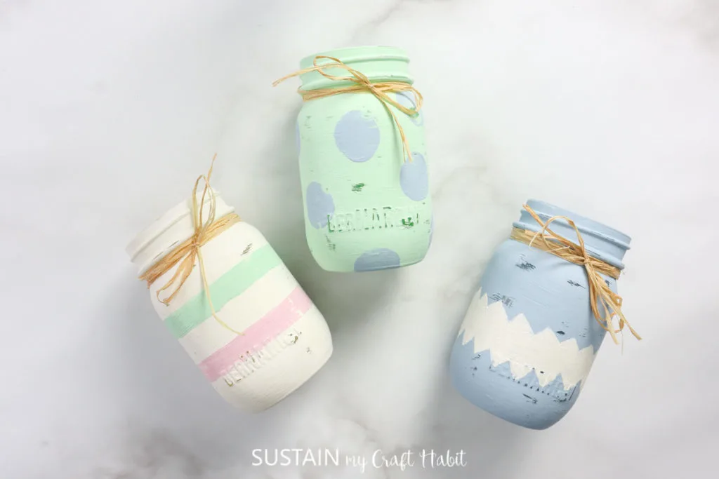 Three painted Easter jars wrapped in ribbon.