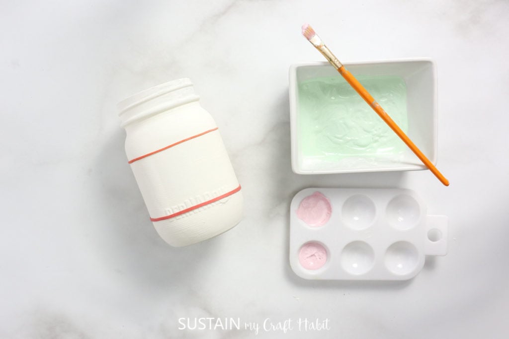 Adding rubber bands around the painted mason jar.