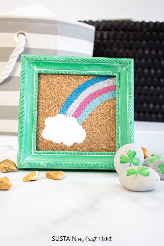 Framed St. Patrick's day craft next to painted rocks.