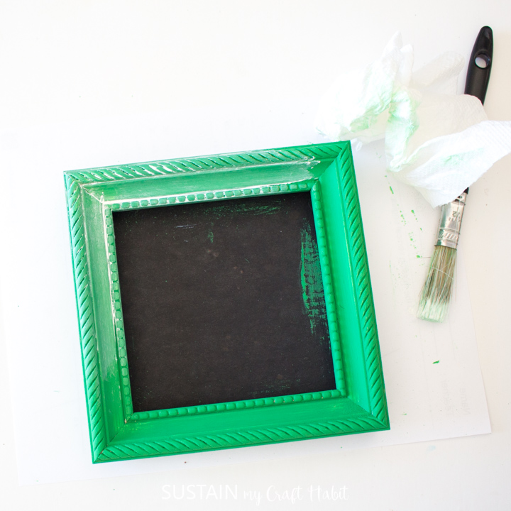 Rubbing the cream wax on a picture frame with a piece of paper towel.