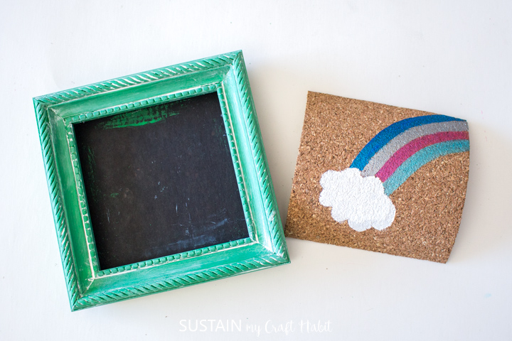 Painted rainbow on a cork sheet next to a green painted picture frame.