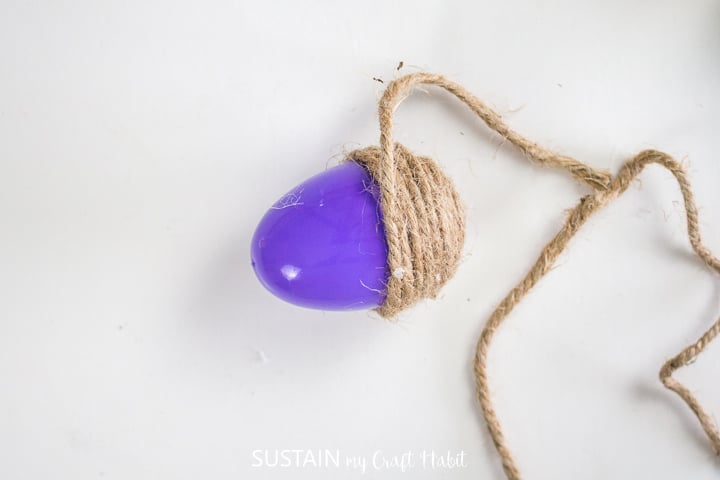 Wrapping twine around a plastic egg.