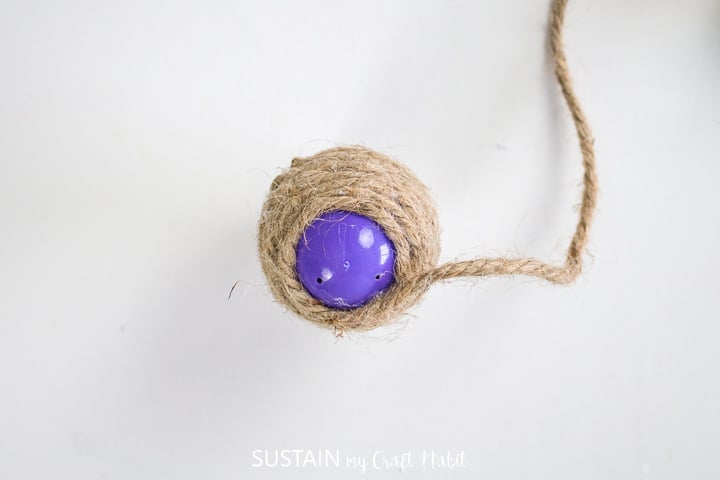 Wrapping twine around a plastic egg.