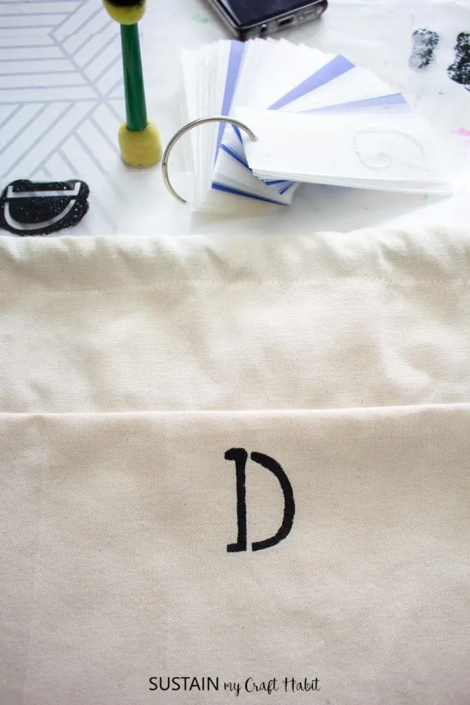 Stencing a letter "D" onto the laundry bag.