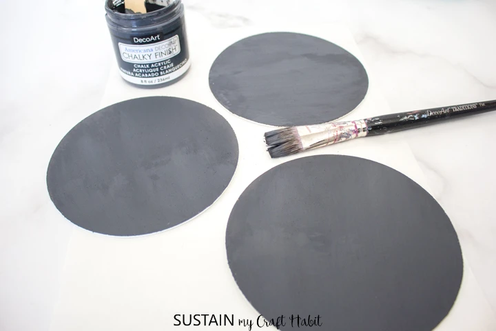 Painting the back of the wood circles with dark grey paint.