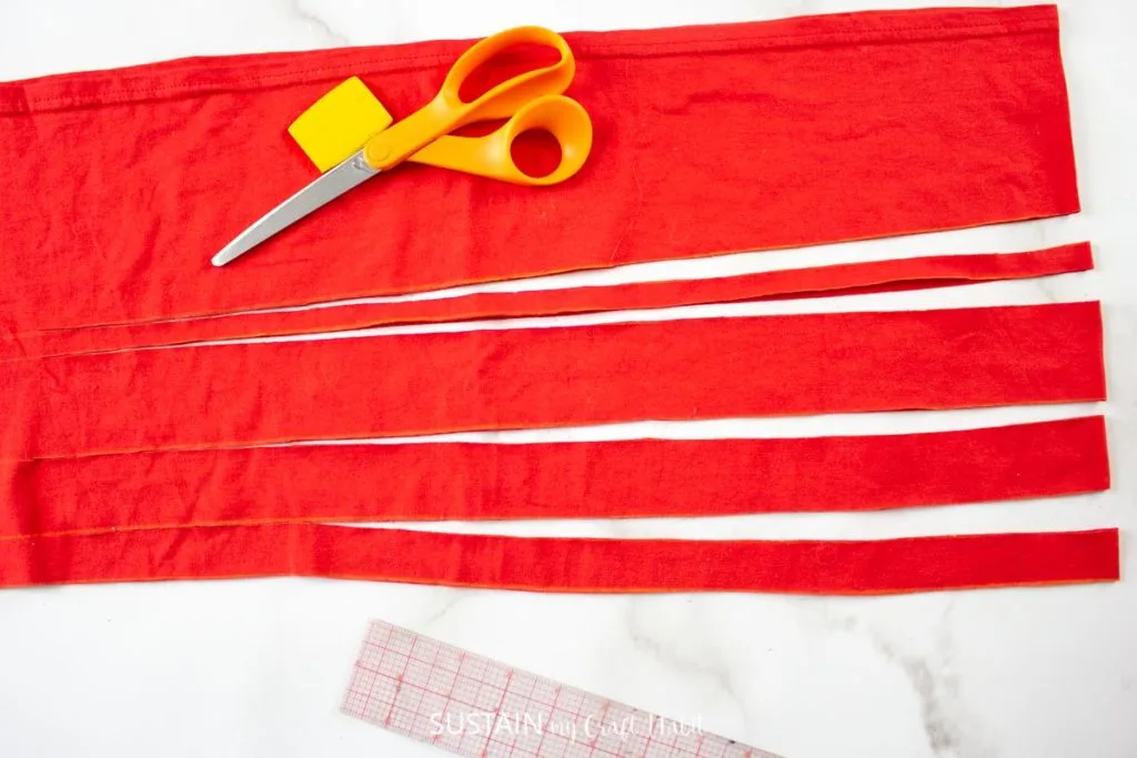 Cutting 1" wide strips into the red tshirt.