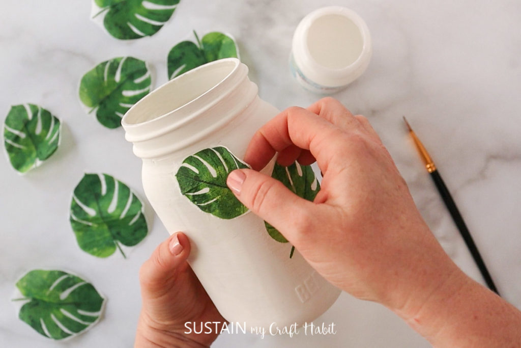 Gluing leaf cut outs onto the glass jar.