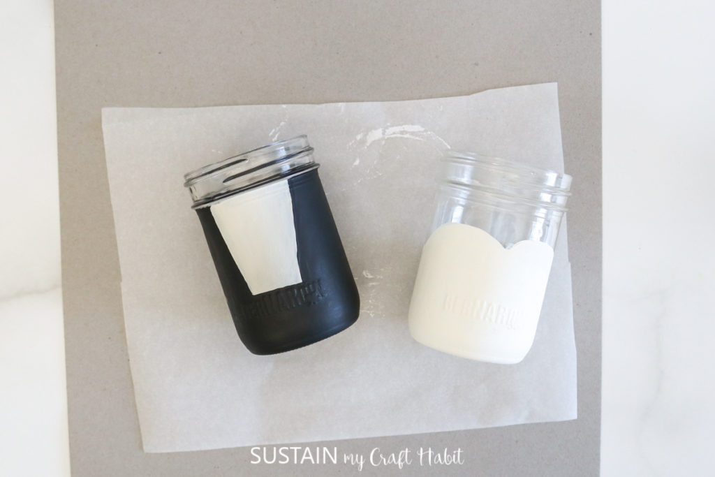 Painting glass jars with white and black paint.