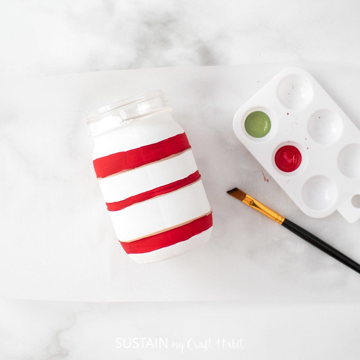 Painting red horizontal lines on the mason jar.