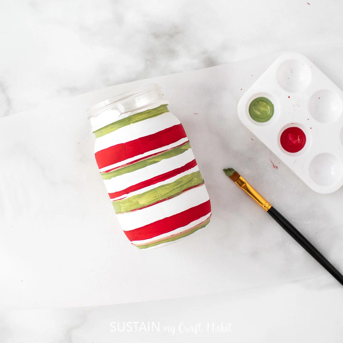 Painting and red and green horizontal lines on the mason jar.