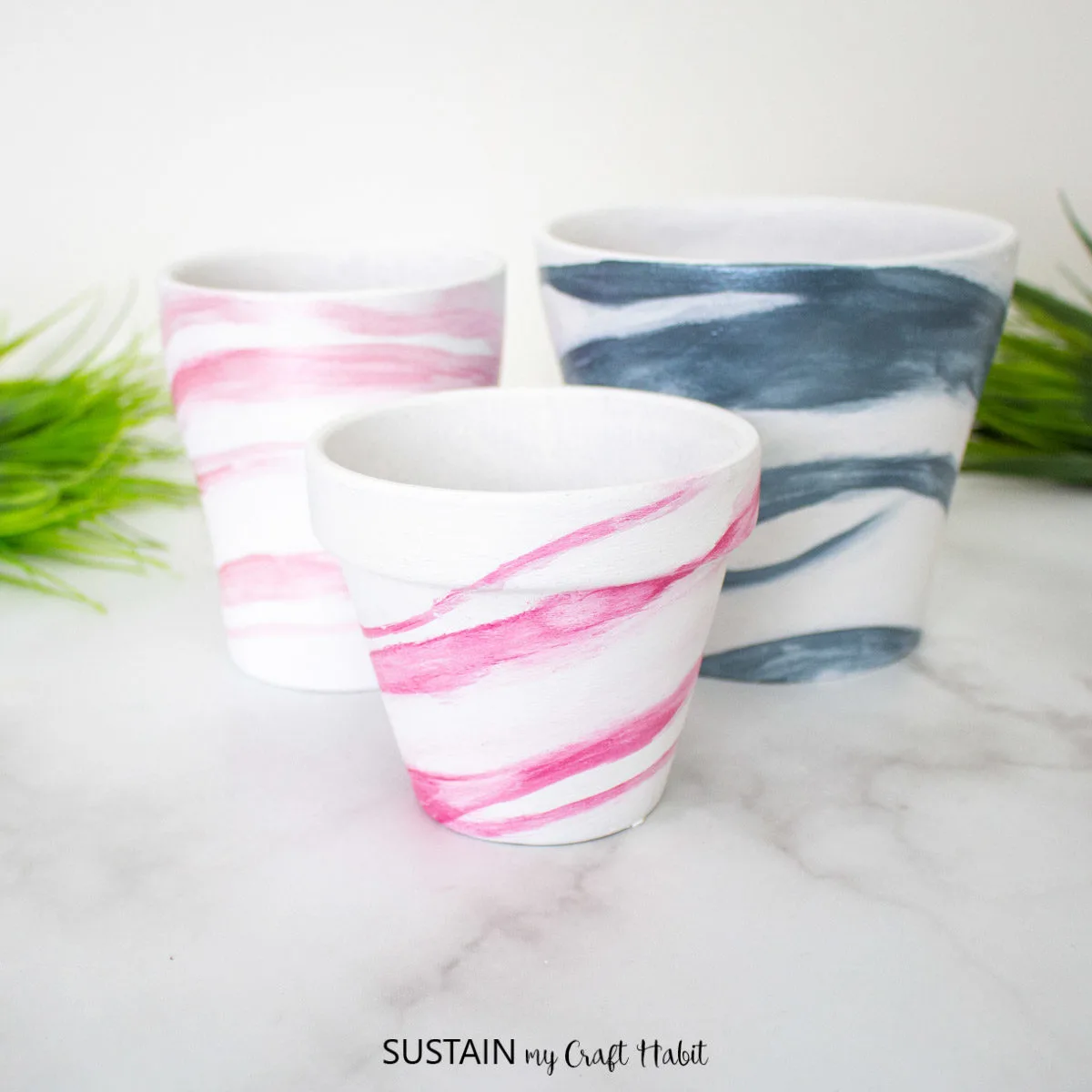 Terracotta pots painted with pink and blue marble effects.
