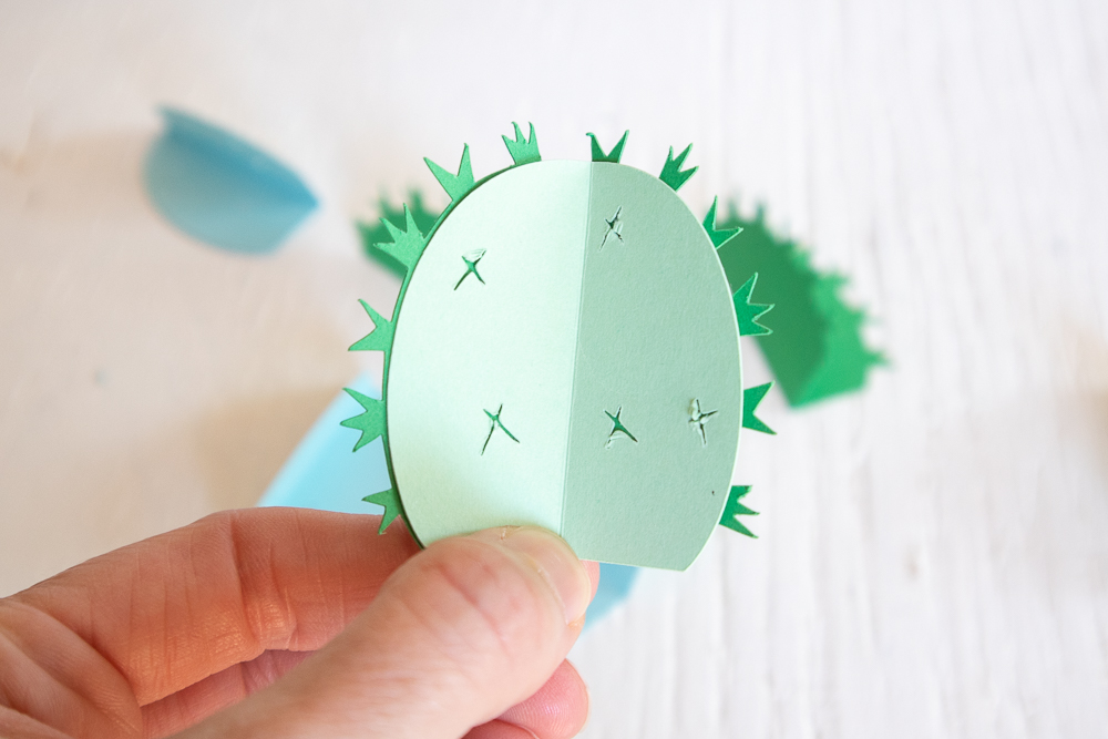 Gluing the folded cardstock together to form the 3D paper cactus.