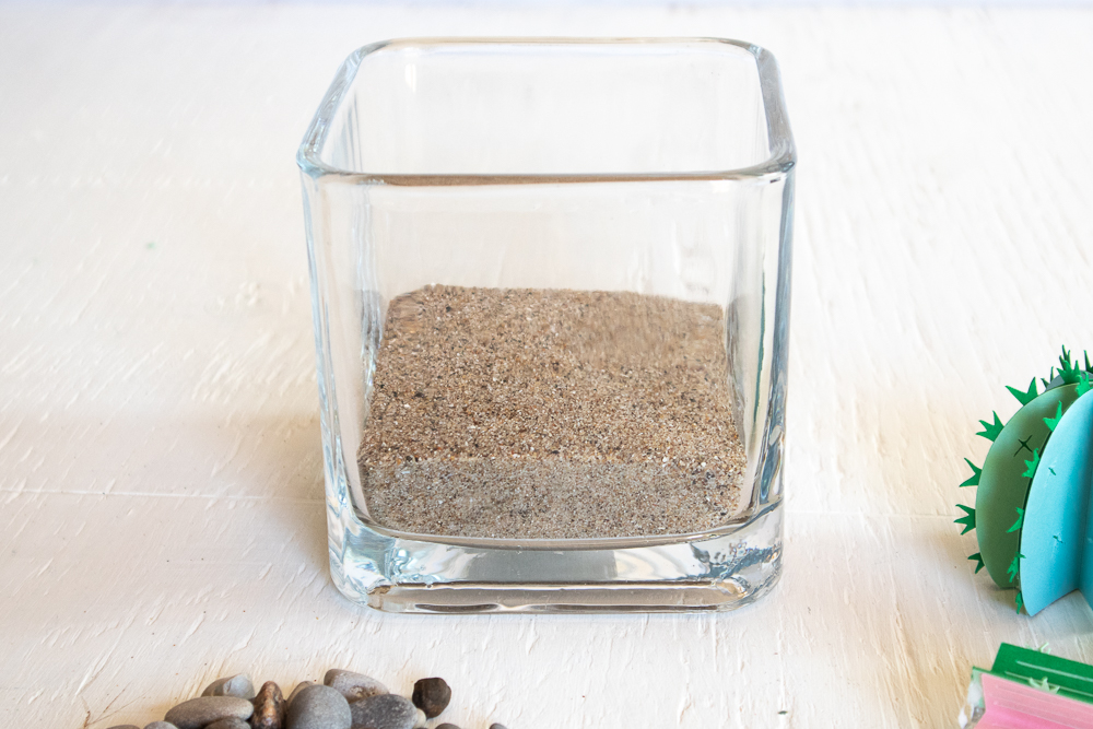 Sand poured into a square glass vase.