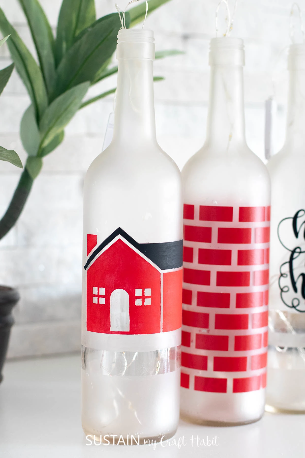 Close up image of the bottle painted with a red and white house using the vinyl stencil cut wiht the Cricut Maker.