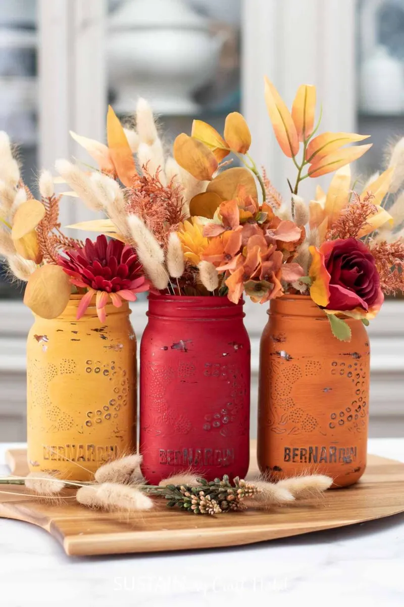 Painted jars for Thanksgiving filled with fall flowers and lagurus bunches.